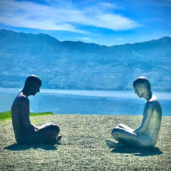 2 statues sitting across each other on hilltop by Luisa I Herrera