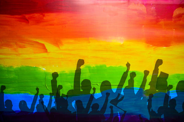 Photo of Pride Flag and shadows of people raising a fist