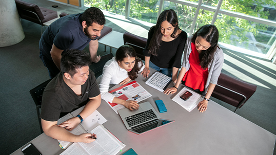 five students using laptop at desk