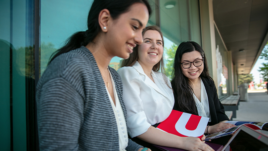 three york students sitting outside on campus in summer