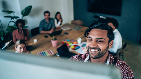 focus on young south asian man at board with his peers in the background