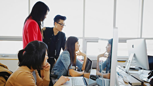 Group of York students gather around laptop and desktop computers in workspace