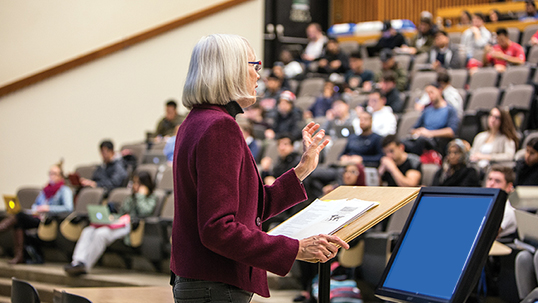 teacher speaking to lecture hall of students