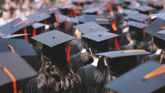 Backside view of university students wearing graduation hats during convocation ceremony.