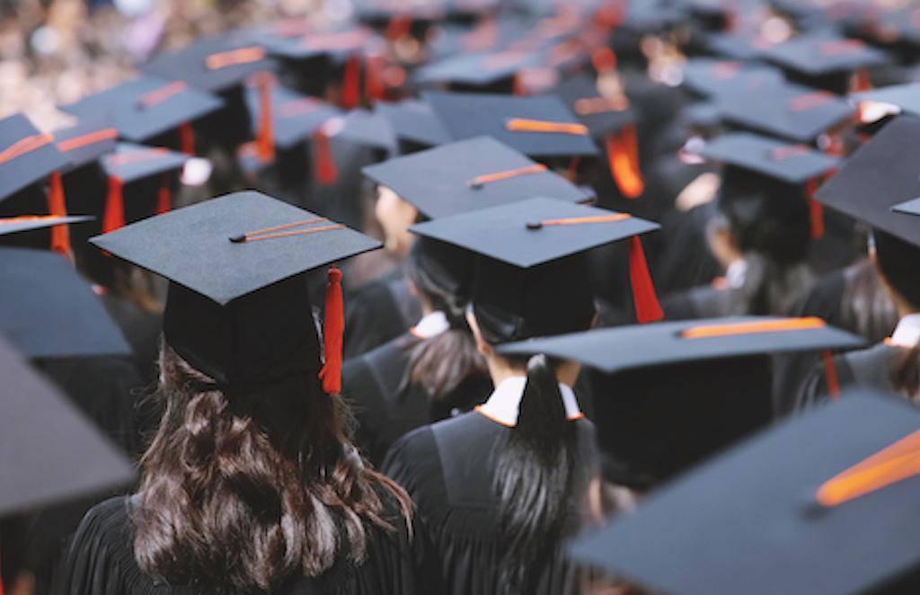 Backside view of students wearing graduation hats during convocation ceremony.