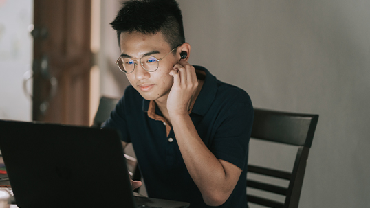 Male student does research on his laptop at his home office