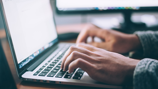 Hands typing on laptop