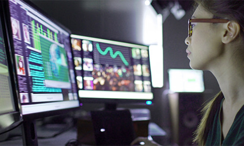 young female researcher studying crime trends on her computer screens