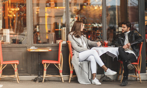 two fashionable young people chatting at cozy french cafe