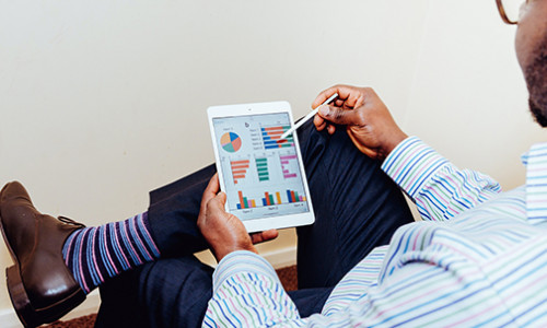 Certificate in Financial Planning business professional tracking his stock performance on a tablet