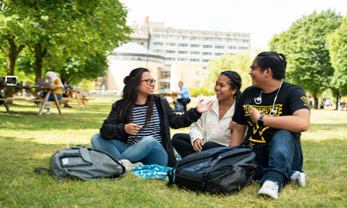 Humanities three yorku students in the shade under a tree at keele campus on summer day