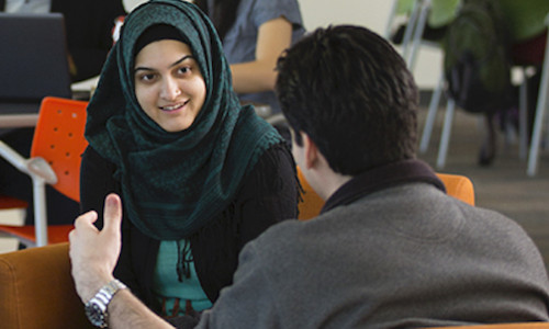 focus on woman in hijab interacting with her peer