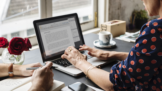 A woman typing a word document on her laptop