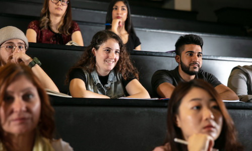 Students sitting down behind lecture hall desks