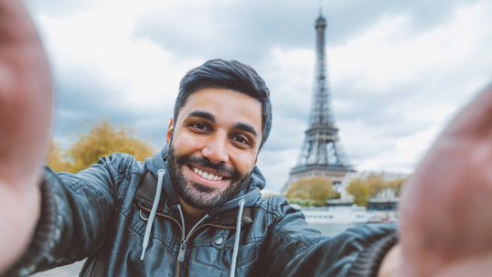 man taking selfie in front of Eiffel tower in Paris 
