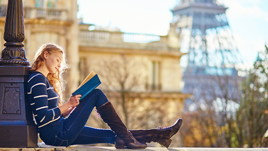 girl reading book in park near Eiffel tower in Paris
