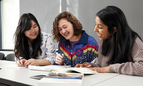 three students studying at desk