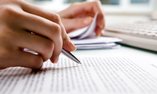 Professional Writing hand holding pen reviewing pages of text