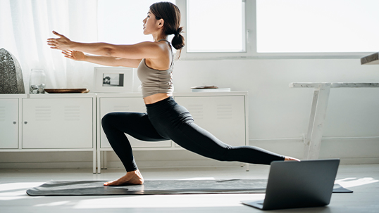woman doing yoga in front of laptop