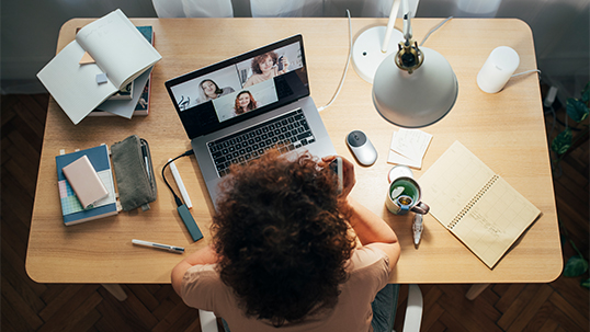 Overhead view of young woman sitting at desk while on video conference call