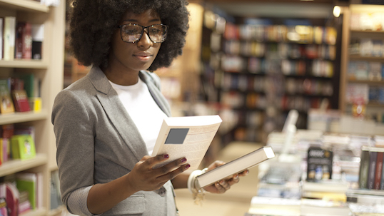 Black woman at bookstore holding books in her hands before making a purchase