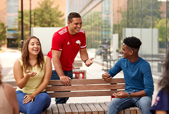 students sitting on the bench in front of student centre on Keele Campus