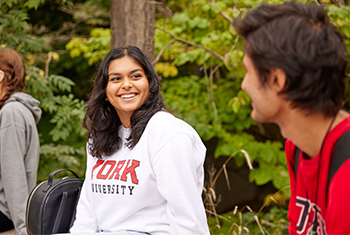 two students sitting outside smiling and talking