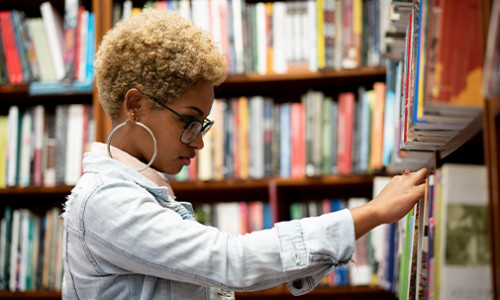 Black female student browses a library for some books.