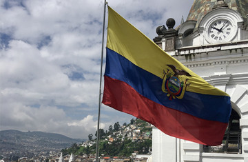 Ecuador flag flying above the Quito skyline.