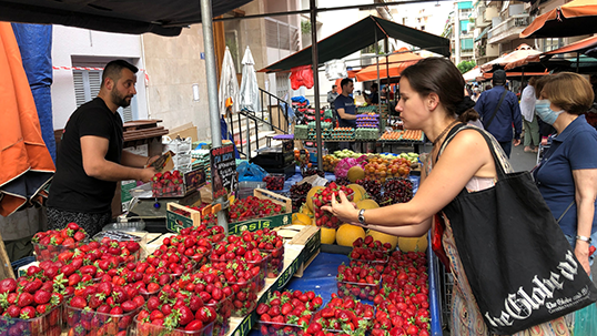 Student gets strawberries at the market in Greece