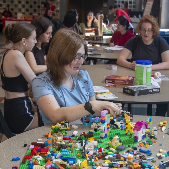 Student sitting at a table putting together a LEGO creation with several different pieces.