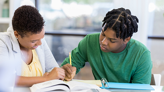 African American student studies for a test. Advisor is helping him.