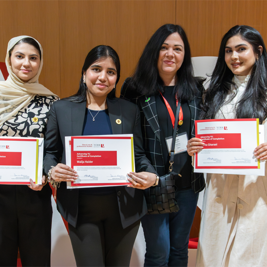 Certificate recipients stand with an event organizer while holding certificates of completion during the Advancing YU Celebration.