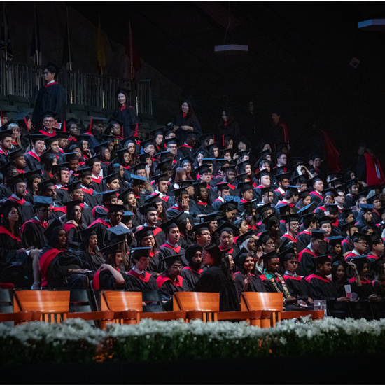 Graduates wearing academic gowns and caps are seated in rows inside a convocation venue before the ceremony begins.