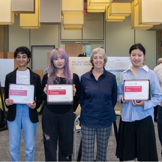Three certificate recipients stand with a presenter while holding award certificates at an academic recognition event