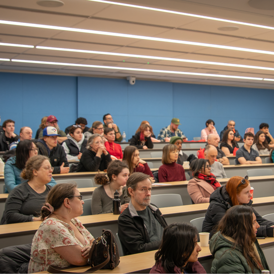 Attendees sit in a lecture hall listening to a presentation during a Spring Open House information session.