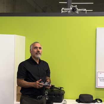 Person operates a drone controller while a drone hovers during a classroom demonstration