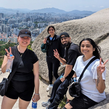 Group of students pose at a scenic overlook during a study abroad trip, with a city skyline in the background