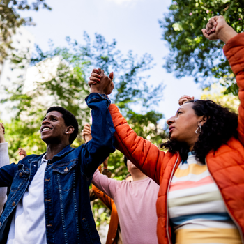 People hold hands in a circle outdoors during a community gathering