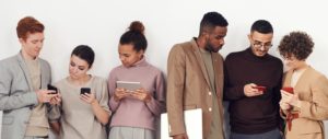 People standing by a white wall holding mobile devices
