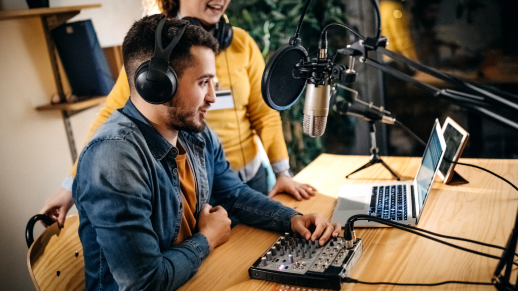 Two people wear headphones and speak into microphones.