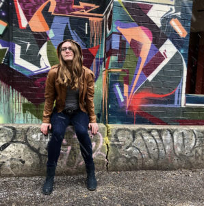 Emily Goodwin leans against brightly coloured outdoor mural