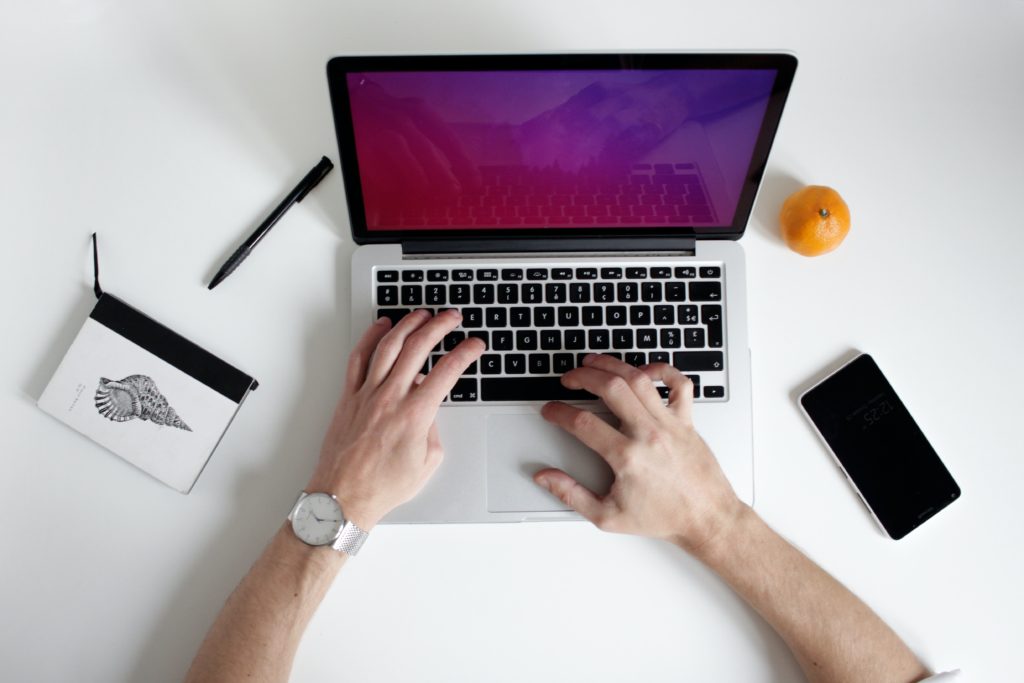 A student’s hands typing on a laptop on a desk.