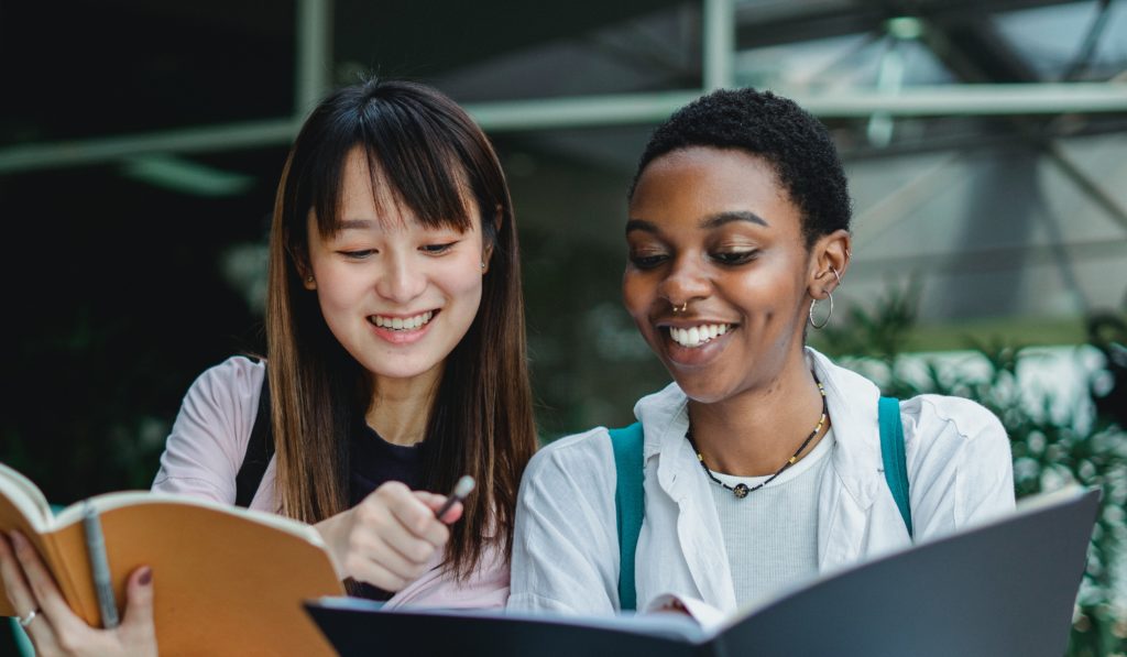 Two people look at notebooks together