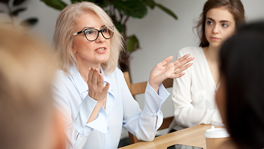 Professor consults with faculty at shared desk