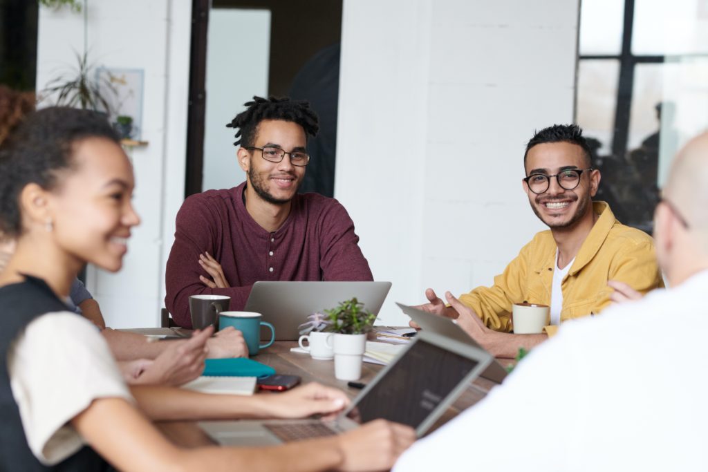 Group of people sitting at a table with laptops