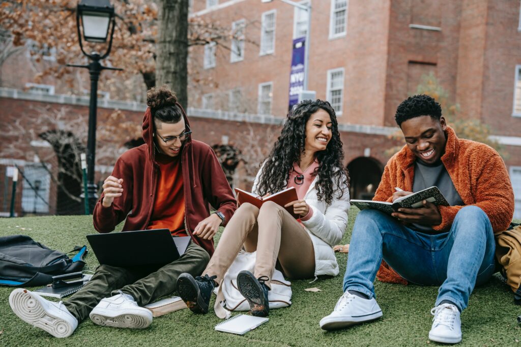 Three students sitting on the grass