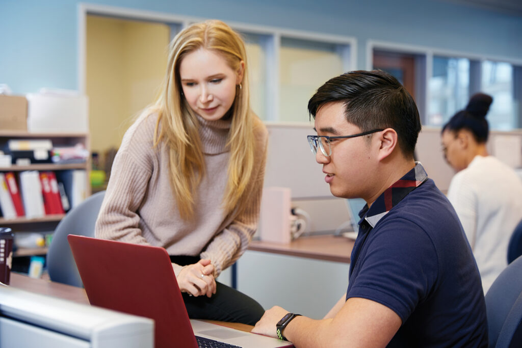 asian man looking at a laptop with a blonde woman beside him