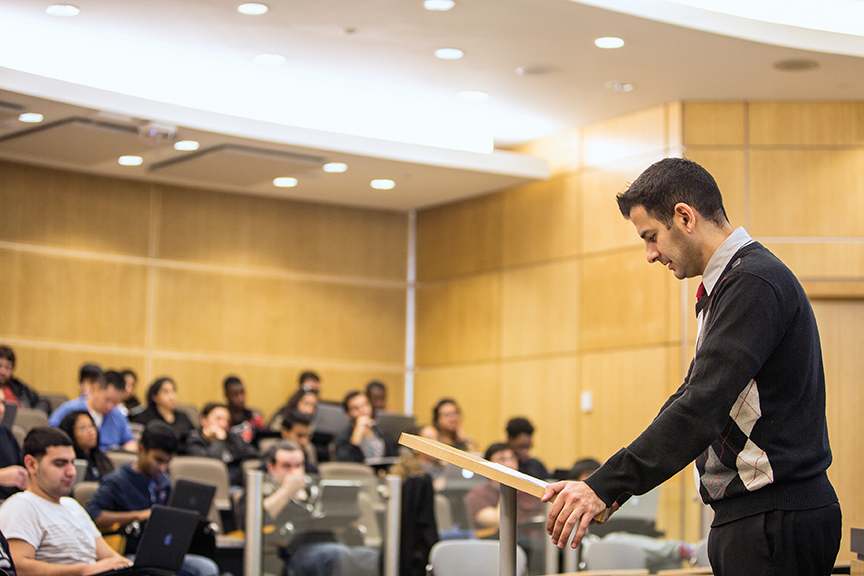 lecturer looking down at the podium in front of an audience