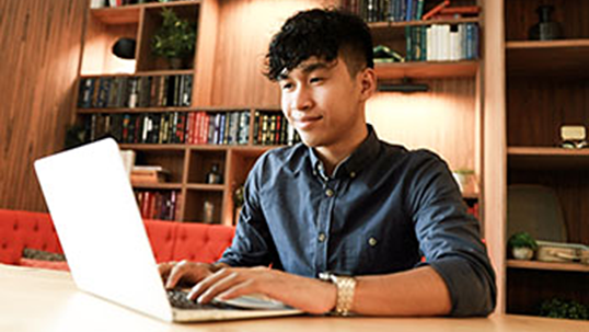 smiling student working on a laptop in a library